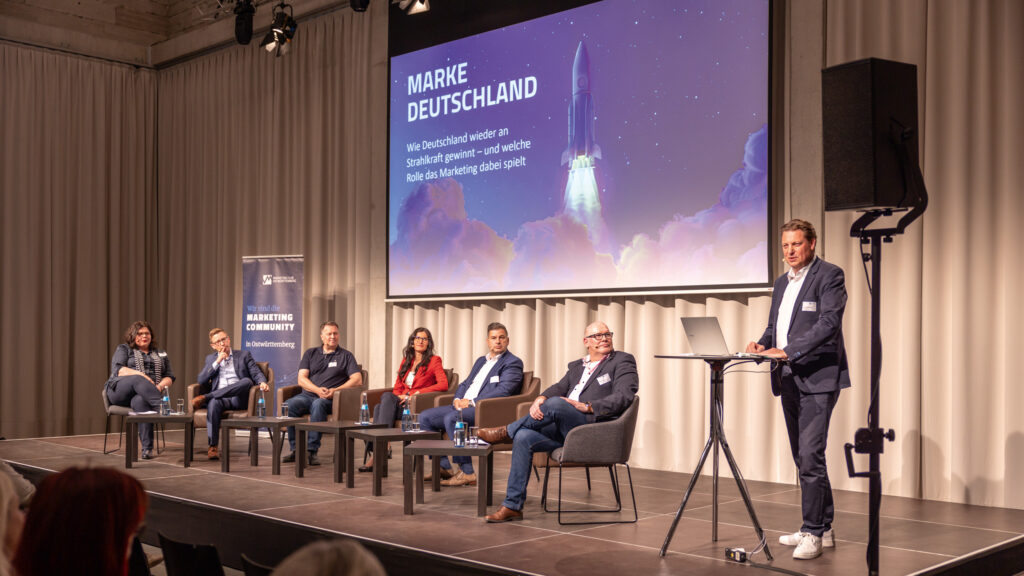 Podium mit Referenten. Claudio Montanini spricht gerade am Mikrofon