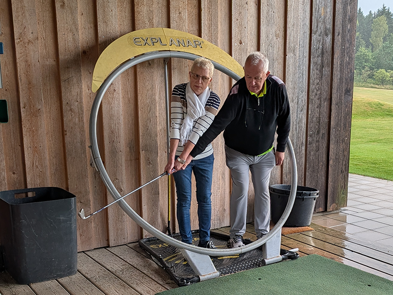 Übung Abschlag eines Teilnehmers innerhalb eines Metallrings. Zusammen mit Golflehrer