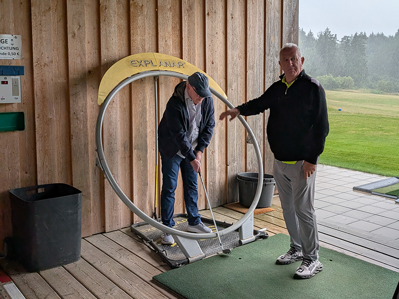 Übung Abschlag eines Teilnehmers innerhalb eines Metallrings. Zusammen mit Golflehrer