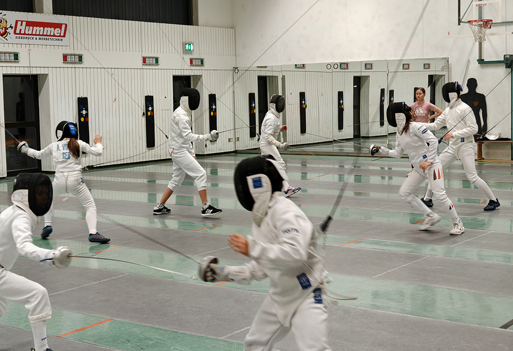 Fechtstunde mit mehreren Fechtern, die sich duellieren