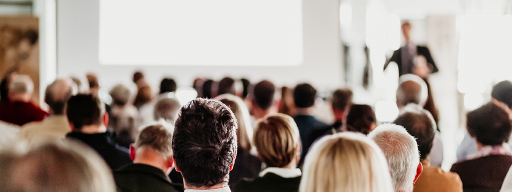 Vortrag: Publikum von hinten und vorne verschwommen der Referent