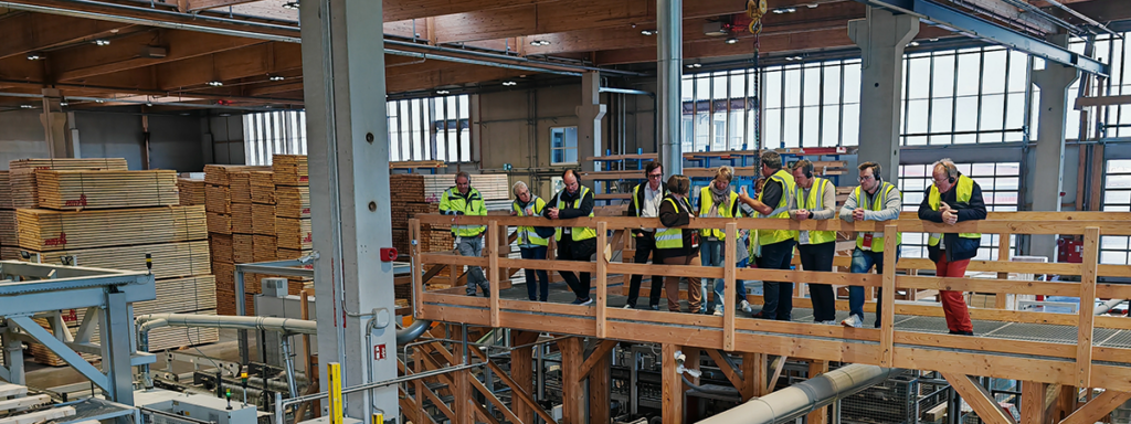 Besuchergruppe steht auf einer Holzbrücke in der Produktionshalle von Ladenburger Holzwerken